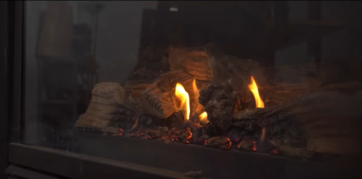 a gas fireplace with a large flame burning inside.